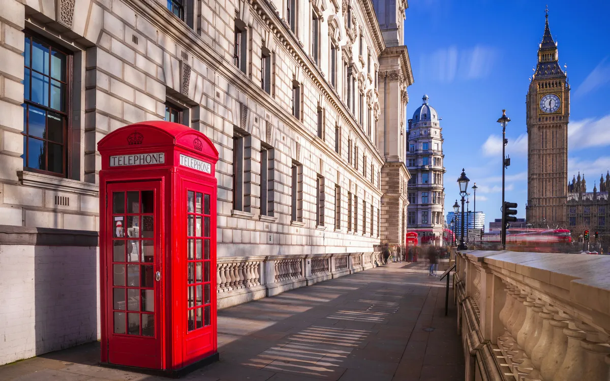 rote Telefonzelle mit Big Ben und Doppeldeckerbus im Hintergrund in London