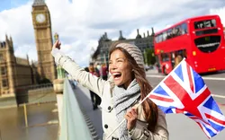 London - glückliche Touristin hält britische Flagge am Big Ben