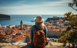 junge Frau mit Rucksack blickt auf Dubrovnik