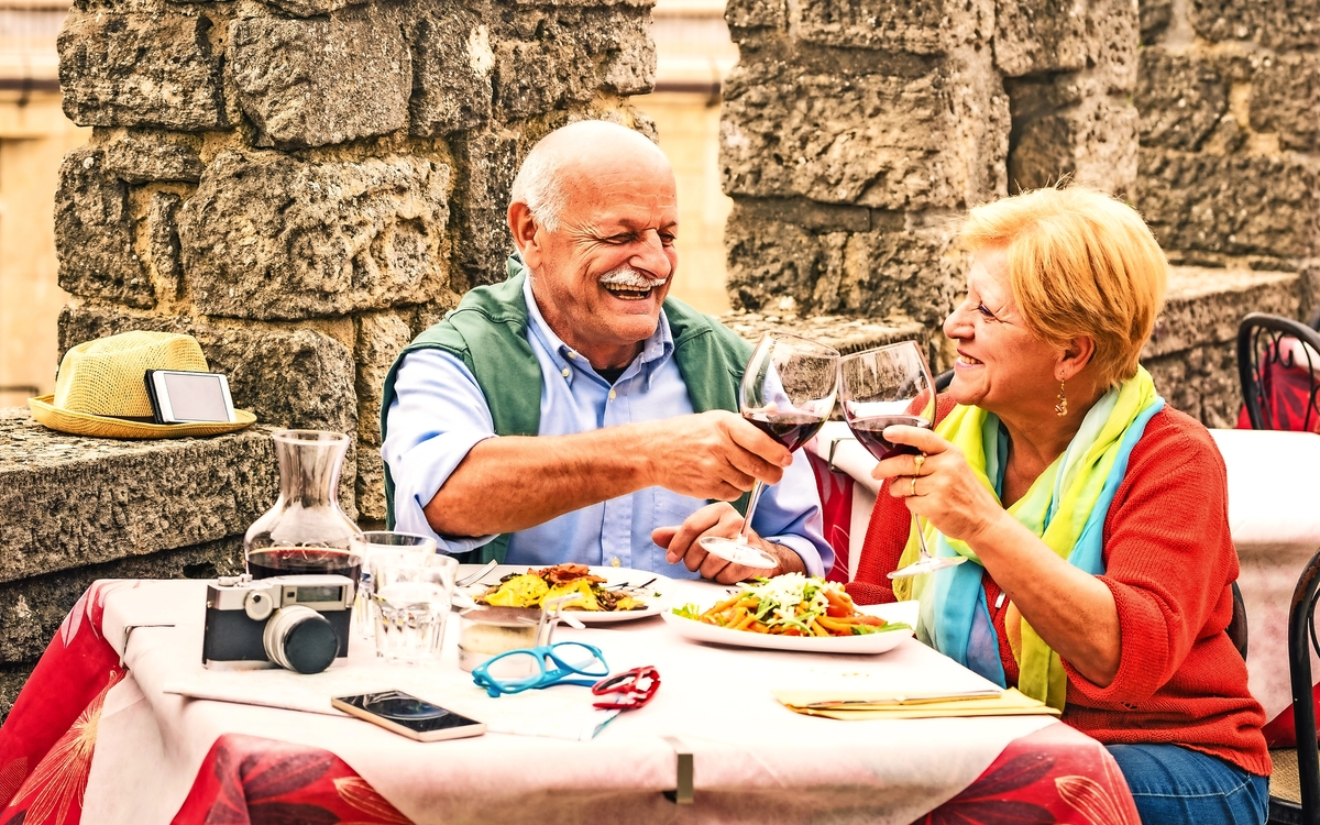 Ältere Paare, die Spaß auf Reisen im Restaurant essen mit - Reife Mann und Frau Frau auf aktive ältere Urlaub - Happy Ruhestand Konzept mit Menschen im Ruhestand zusammen - Warm bewölkten Tag Farbtöne