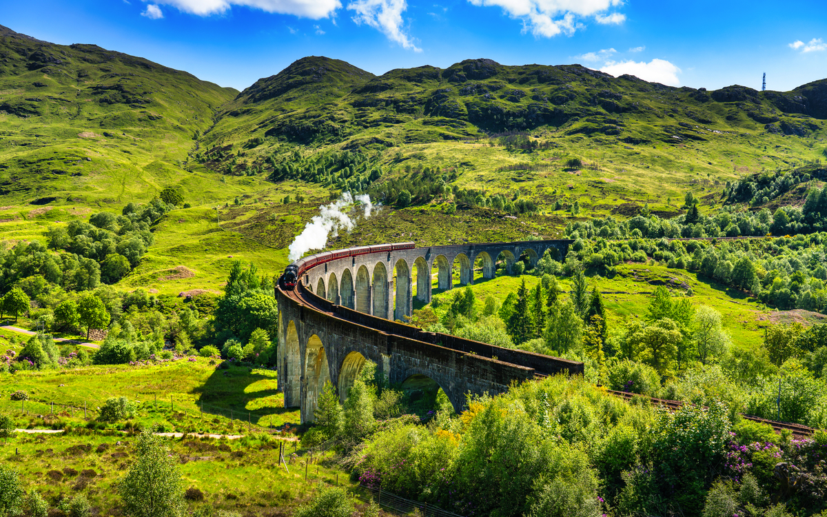 Glenfinnan Railway Viaduct in Schottland mit dem darüberfahrenden Dampfzug
