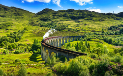 Glenfinnan Railway Viaduct in Schottland mit dem darüberfahrenden Dampfzug