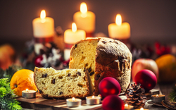 Köstlicher Panettone auf Weihnachtstisch mit Dekorationen und Adventskranz und Kerzen