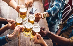 Eine Gruppe von Leuten genießt und stößt mit einem Bier in der Brauereigaststätte an.