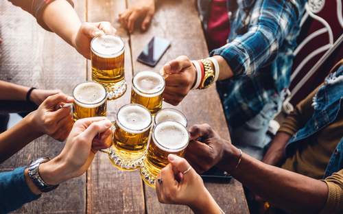 Eine Gruppe von Leuten genießt und stößt mit einem Bier in der Brauereigaststätte an.