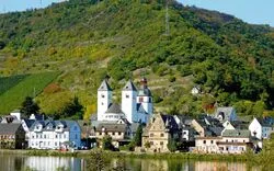 Stadtansicht von Zell an der Mosel mit Kirche und umliegenden Hügeln.