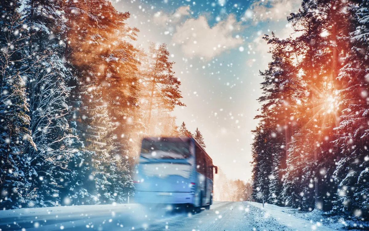 Bus auf Asphaltstraße an einem schönen Wintertag auf dem Land bei Schneefall