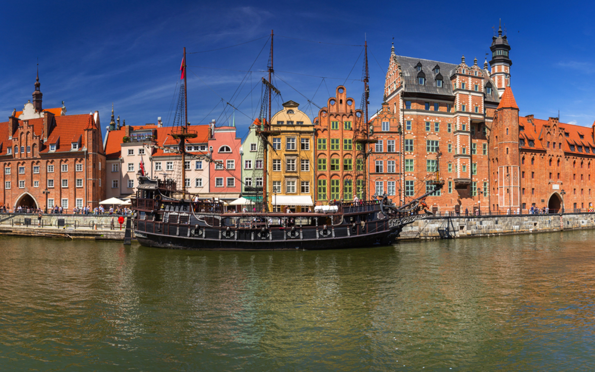 Panorama der Altstadt von Danzig mit historischem Hafenkran, der sich im Fluss Mottlau spiegelt