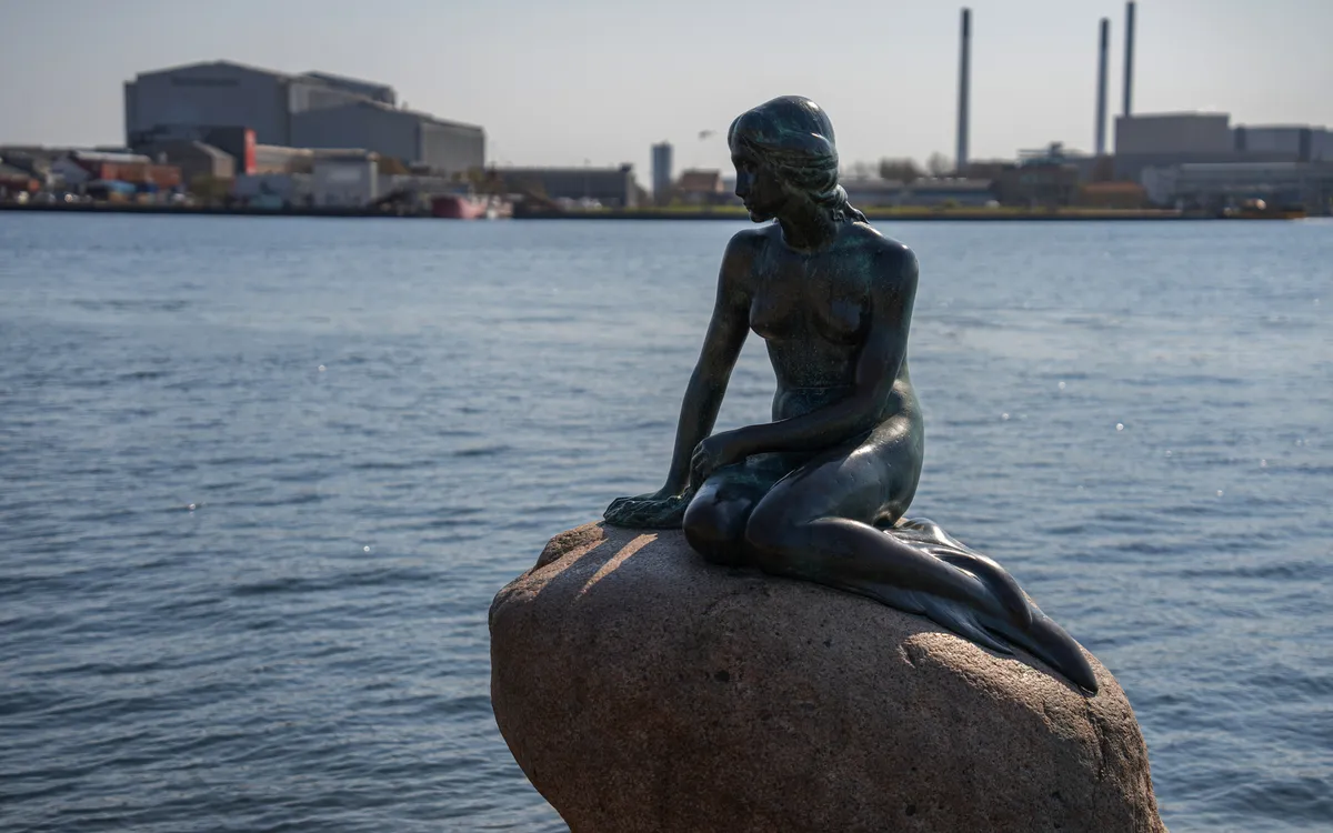 Statue der kleinen Meerjungfrau mit Blick auf den Hafen in Kopenhagen