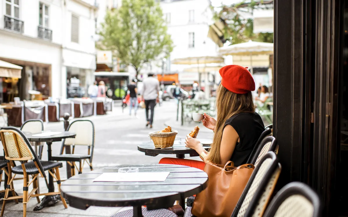 Frau mit einem französischen Frühstück im Café