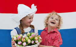 Holländische Kinder mit Tulpenblüten und niederländischer Flagge,