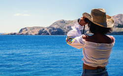 Frau schaut mit Fernglas aufs adriatische Meer