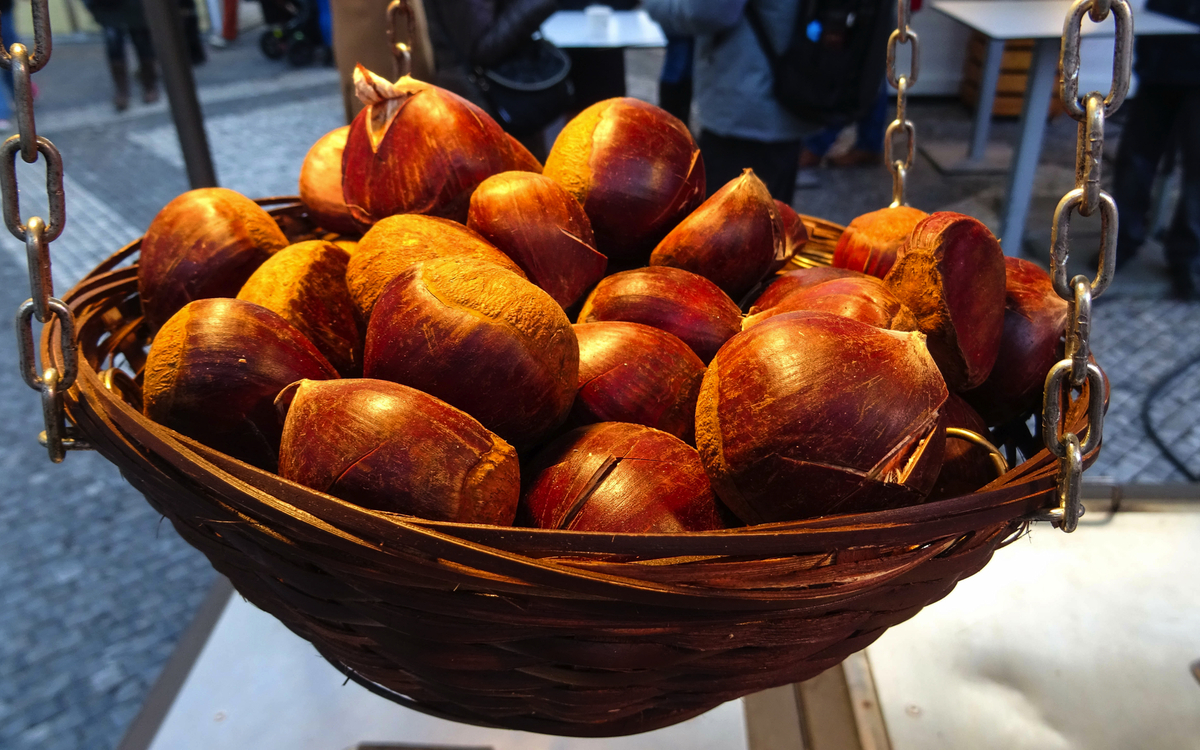 kleiner Korb mit gerösteten Kastanien, die auf dem traditionellen Weihnachtsmarkt auf dem Altstädter Ring verkauft werden, Prag