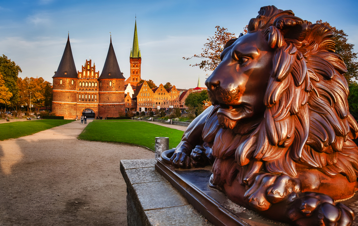Backstein-Löwenstatue vor dem Holstentor in Lübeck bei Sonnenuntergang.