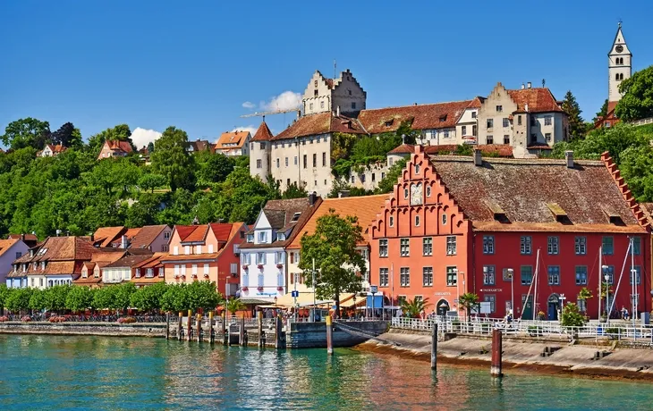 Bunte Häuser am Hafen mit Burg im Hintergrund an einem sonnigen Tag