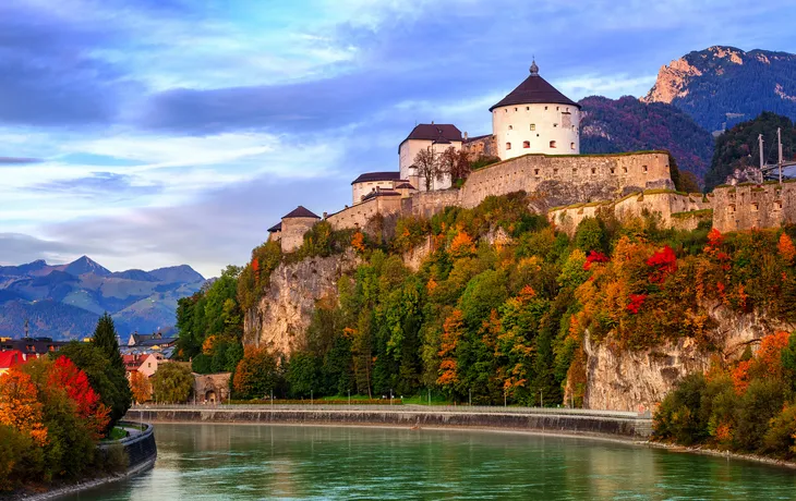 Festung auf einem Hügel am Fluss, umgeben von Herbstbäumen.
