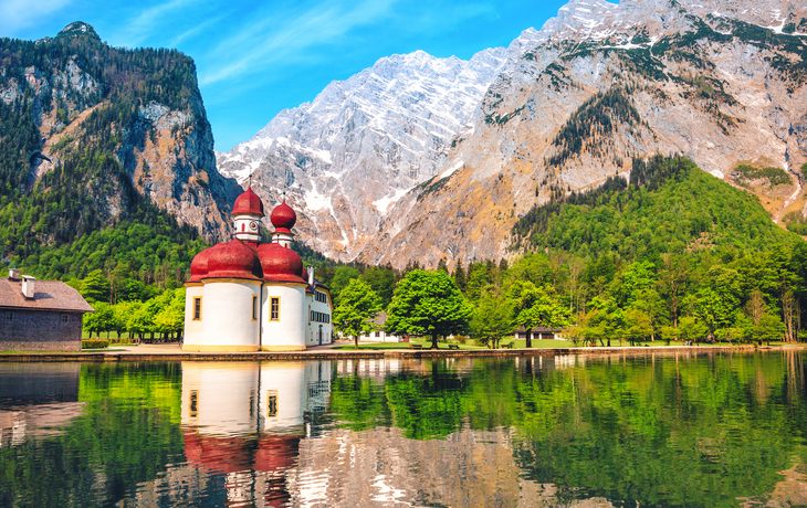 Kirche St. Bartholomä am Königssee mit Bergen im Hintergrund.