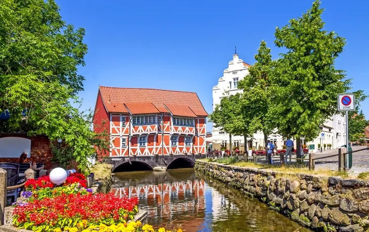 Fachwerkhaus über einem Kanal mit bunten Blumen in einer Altstadt.