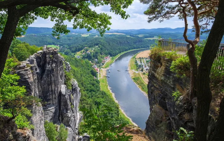 Felsformation mit Blick auf Fluss und Waldlandschaft im Sommer.