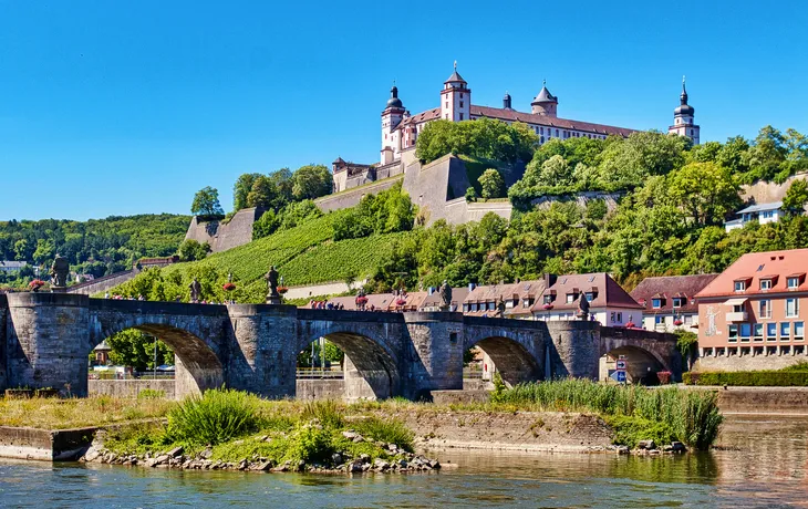 Burg auf einem Hügel über einer Brücke und Fluss, sonniger Tag