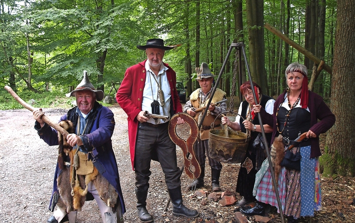 Fünf Menschen in historischen Räuber-Kostümen im Wald stehend.