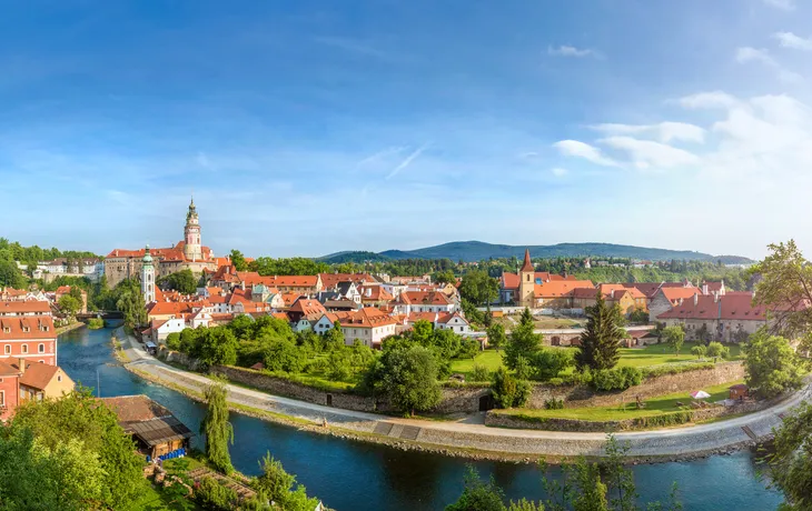Panoramablick auf eine malerische Stadt mit Fluss und roter Ziegeldacharchitektur.