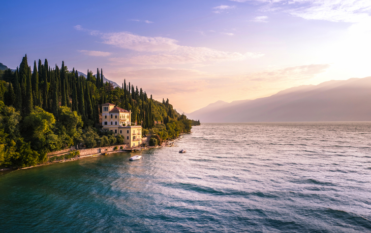 Historische Villa am Gardasee nahe Toscolano Maderno, umgeben von Zypressen und Wasser.