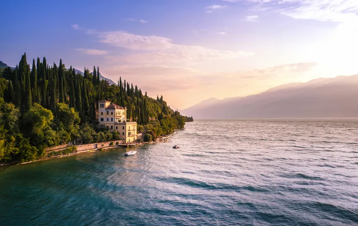 Historische Villa am Gardasee nahe Toscolano Maderno, umgeben von Zypressen und Wasser.