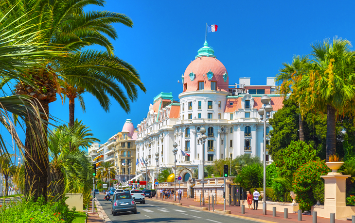 Boulevard in Nizza mit Hotel und Palmen im Vordergrund.