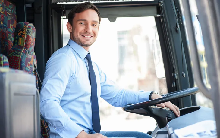 Mann in Hemd und Krawatte am Steuer eines Busses.